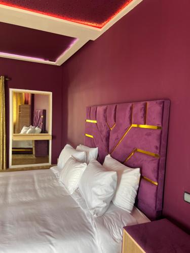 a bedroom with a large bed with purple walls at Auberge Billionaire in Fez