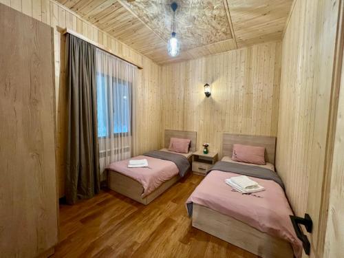 two beds in a room with wooden walls and wood floors at Milenium magic villa on Sevan beach in Sevan