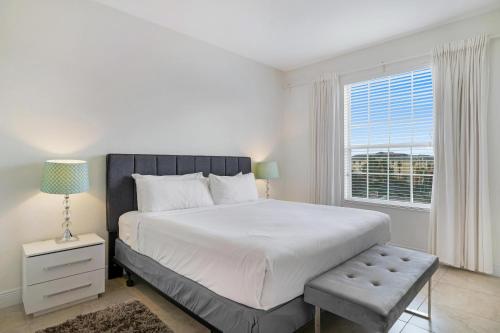 a white bedroom with a large bed and a window at Updated Condo Near Conv Ctr, I-Drive & Universal in Orlando