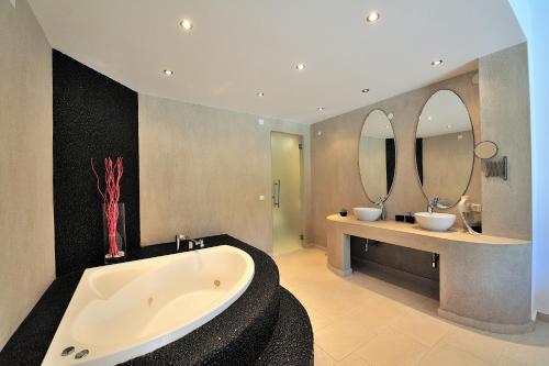 a bathroom with two sinks and a tub and two mirrors at Golden King Villas in Vassilias
