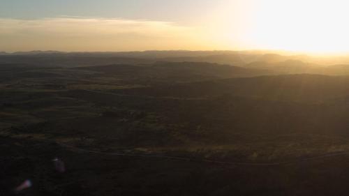 an aerial view of a valley with the sun setting at El Secreto en las Sierras in Villa Serrana