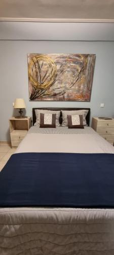 a bedroom with a large bed with a painting on the wall at Μεγάλος χώρος με Γυμναστήριο-Χαμάμ-Κρεβάτι-Γραφείο in Krionérion