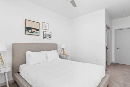a white bedroom with a white bed and a table at CozySuites l Trendy 2BR, Bottleworks Indy #1 in Indianapolis