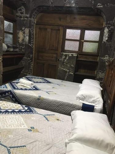 Cabaña Las Caballerizas في تيكوزاوتلا: سريرين في غرفة بها نافذتين