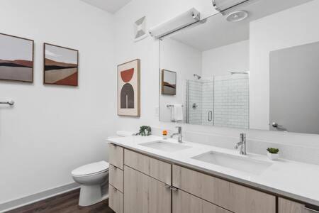 a bathroom with two sinks and a toilet and a mirror at CozySuites l Trendy 2BR, Bottleworks Indy #1 in Indianapolis