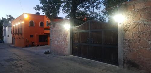 una casa naranja con una puerta de madera y un edificio en Cabaña Las Caballerizas, en Tecozautla