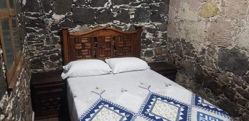 1 dormitorio con 1 cama en una pared de piedra en Cabaña Las Caballerizas, en Tecozautla