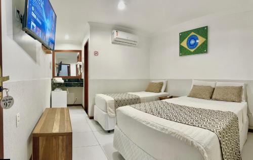 a hotel room with two beds and a tv at Vila Jeri Hotel in Jericoacoara