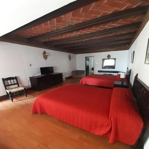 um quarto com duas camas vermelhas e um piano em villa de la plata em Guanajuato