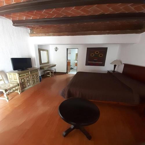 um quarto com uma cama, uma cadeira e uma televisão em villa de la plata em Guanajuato