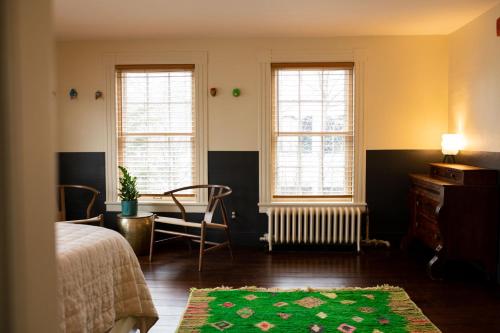 a bedroom with a bed and a table and two windows at The Vesper Woodstock in Woodstock