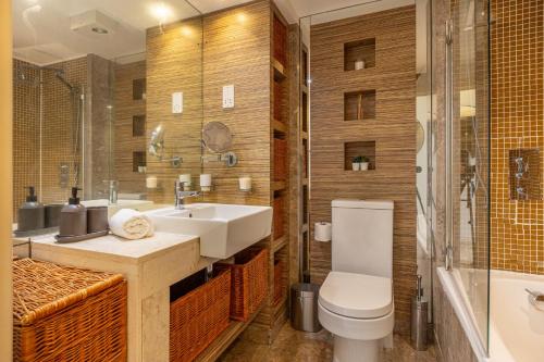 a bathroom with a sink and a toilet and a tub at Corporate Canary Suite in London