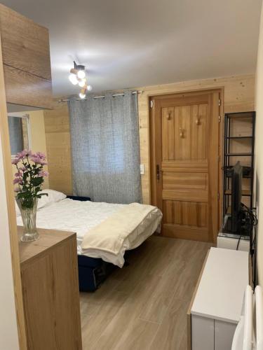 Chalet Lou Via location في أبودونس: غرفة نوم بسرير و إناء من الزهور