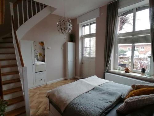 a bedroom with a bed and a staircase with windows at Gemütliche Ferienwohnung in Neu Kaliß in Neu Kaliß
