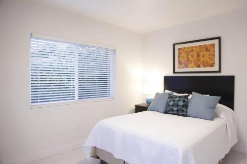 een witte slaapkamer met een bed en een raam bij Apt 3 Miami Designer Apartment in the Upper East-Side in Miami