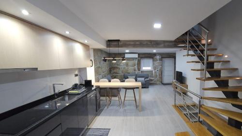 a kitchen and living room with a table and a staircase at Casa da Póvoa in Seia