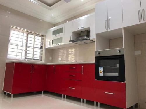 una cucina rossa con armadi bianchi e piano cottura di Paradise estate a Accra