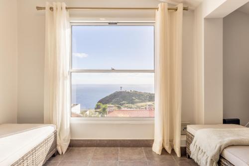 a bedroom with a large window with a view of the ocean at SUNSET VILLA in Caniço