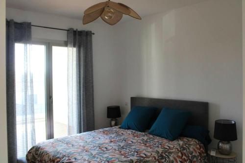 une chambre avec un lit avec des oreillers bleus et une fenêtre dans l'établissement Appartement moderne à Grosseto-Prugna, vue montagne, 50 m², à Grosseto-Prugna