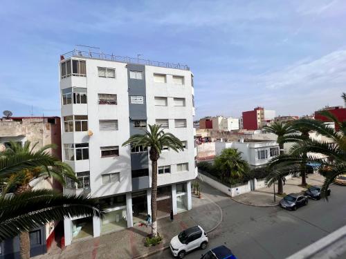 um edifício branco com uma palmeira em frente em Appartement Lallaty em Rabat