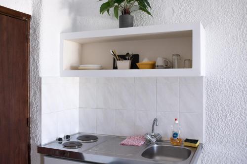 un bancone da cucina con un lavandino e uno scaffale di Haniotis Studios a Faliraki