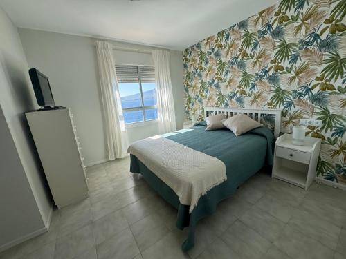 1 dormitorio con 1 cama con papel pintado tropical en Un lujoso duplex en Radazul en primera linea de playa y con parking propio, en Radazul