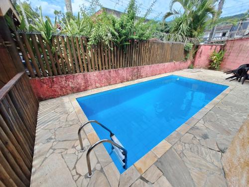 a swimming pool in a backyard with a wooden fence at Sobrado bem localizado em Praia de Boiçucanga in São Sebastião