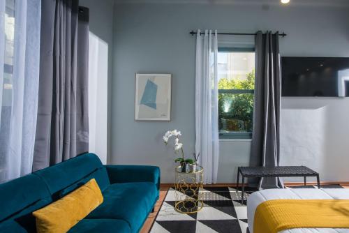 a living room with a blue couch and a window at Korai Suites by Good Life in Heraklio Town