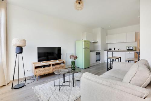 un salon avec un canapé et une télévision et une cuisine dans l'établissement La Résidence Alpha Viroflay 102 - 1 chambre - 2 pers, à Viroflay