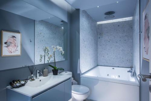 a bathroom with a tub and a toilet and a sink at Korai Suites by Good Life in Heraklio Town