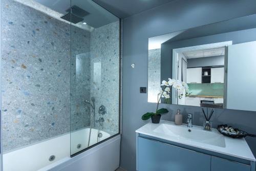 a blue bathroom with a tub and a sink at Korai Suites by Good Life in Heraklio Town