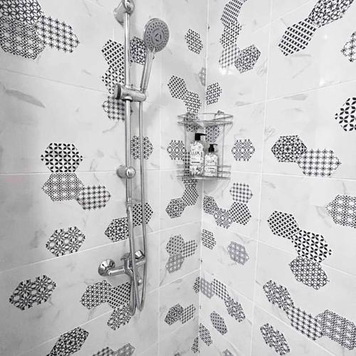a shower with a black and white pattern on the wall at Нощувки Хранова in Plovdiv