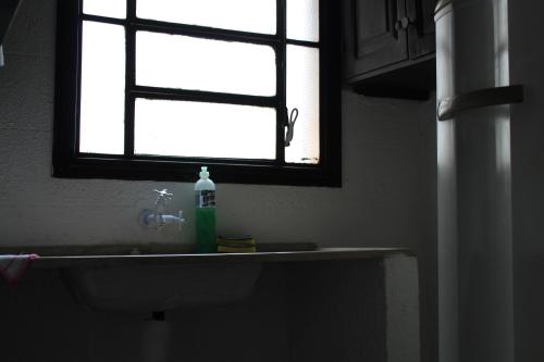um lavatório de casa de banho com uma janela e uma garrafa de sabão em Kaburei Ap 7 em Ciudad del Este