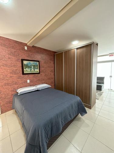 1 dormitorio con cama y pared de ladrillo en Kitnet 02, en Rio Negrinho