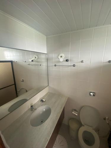 a bathroom with a sink and a toilet and a mirror at Apartamento em frente ao Laguinho in Salinópolis