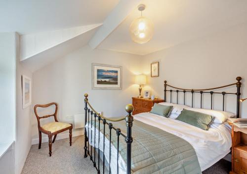 a bedroom with a bed and a chair at Tan Yr Orsedd in Abersoch