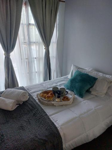 een bed met een dienblad met donuts en kopjes en een bord met eten bij Linas Apart & Suite in La Rioja