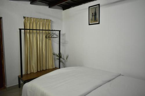 ein weißes Schlafzimmer mit einem Bett und einem Fenster in der Unterkunft IKIAM- in Nature's Embrace in Mānantoddy