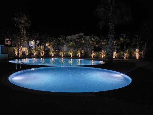 uma grande piscina de água azul à noite em Pitagora Residence em Metaponto