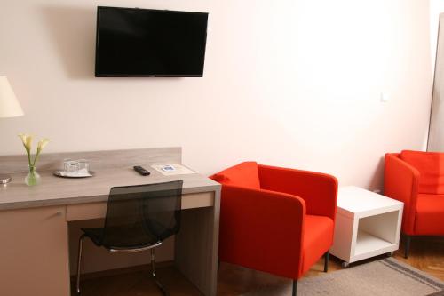 Habitación con escritorio y 2 sillas rojas. en Hotel Klara, en Praga