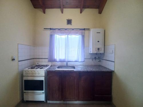 a small kitchen with a stove and a window at Tantanakuy 2 in Villa General Belgrano
