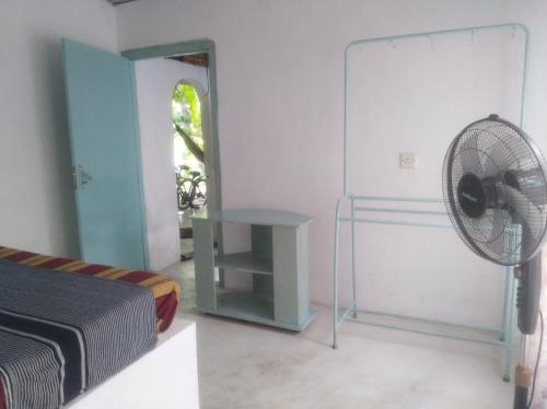 1 dormitorio con 1 cama, escritorio y ventilador en Piyo Vida Guesthouse en Ahangama