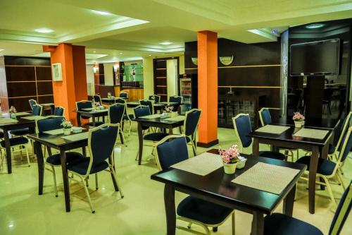 a restaurant with tables and chairs and a flat screen tv at Hotel Le Village Distributed By Intercity in Joinville