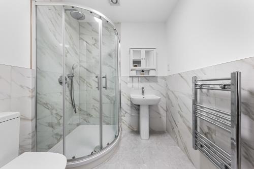 a white bathroom with a shower and a sink at 3 Bedroom Sleep12 in London MR2 in London