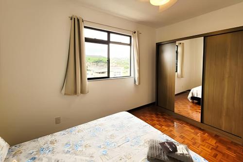 1 dormitorio con cama y espejo grande en Nosso Apê Andradas: Apartamento com Garagem NA0701 en Juiz de Fora
