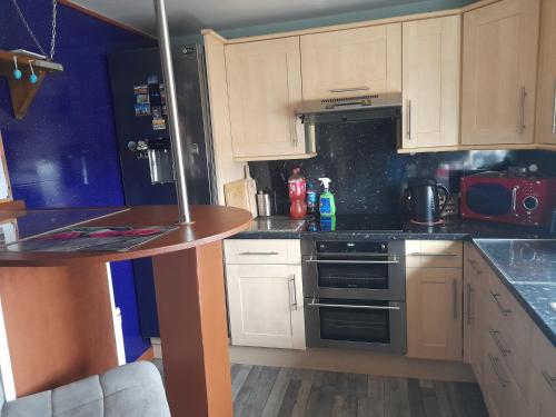 uma cozinha com armários brancos e um forno com placa de fogão em Bastolino em Newtongrange