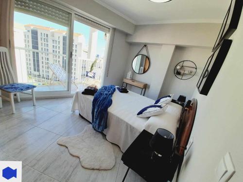 a bedroom with a bed and a large window at Apartamento de Pescado Azul Gandia playa con piscina ascensor y vistas al mar in Playa de Gandia