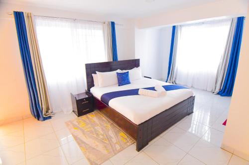 a bedroom with a bed and two large windows at Visibly elegant in Kisumu