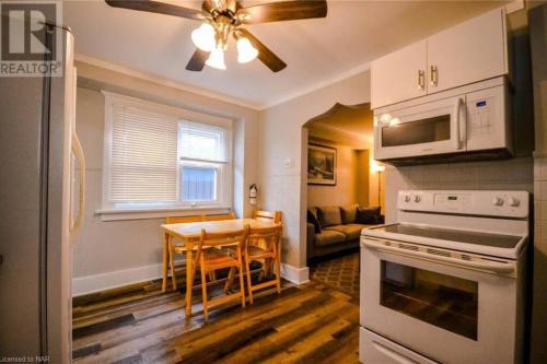 a kitchen with a table and a ceiling fan at Cozy 3 Bedroom Downtown Hideaway Cottage with Complimentary Breakfast in Niagara Falls