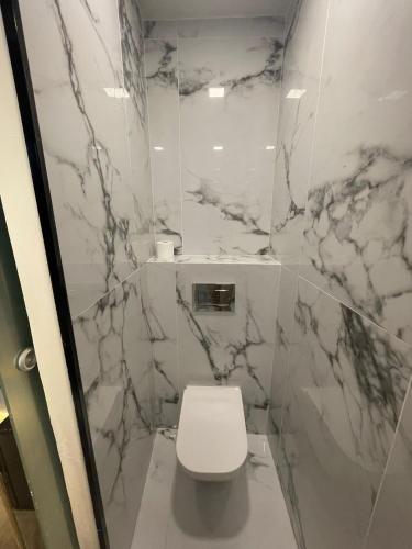 a bathroom with a white toilet and marble walls at PAIISE Hotels in Sant Francesc de s'Estany